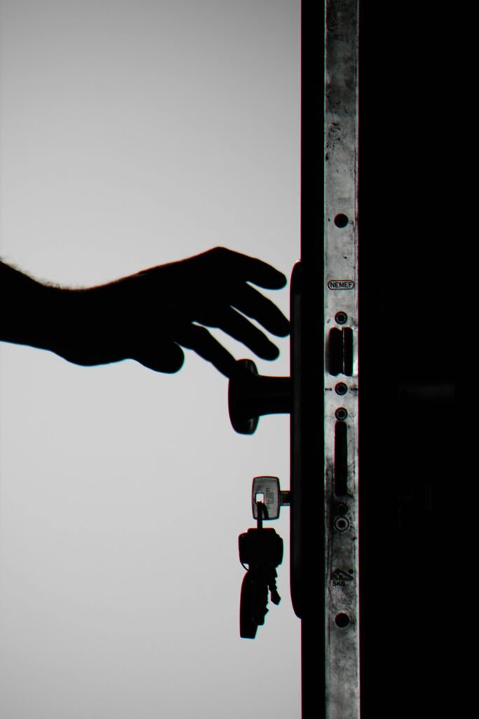 Silhouette of a hand about to open a door with keys in lock, symbolizing security.